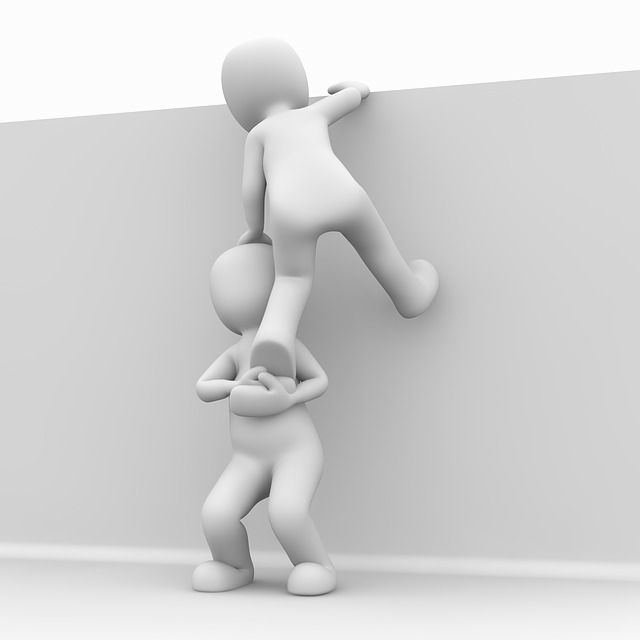 Eine Person hilft einer anderen mit der Räuberleiter an etwas hochzuklettern.